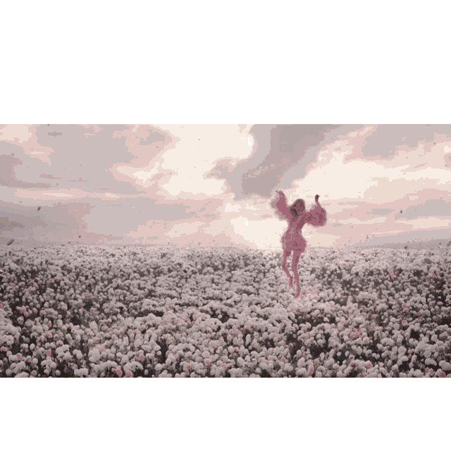 a woman in a pink dress standing in a field of flowers