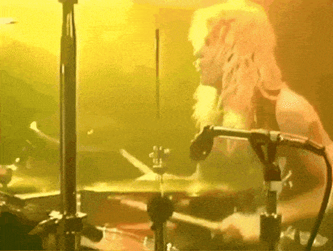 a woman is playing drums in front of a yellow background