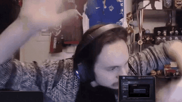 a man wearing headphones is playing a video game on a laptop .