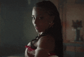 a woman in a red bra is standing in a dark room and looking at the camera .