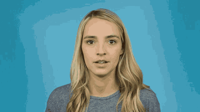 a woman with blonde hair and a gray shirt is making a funny face