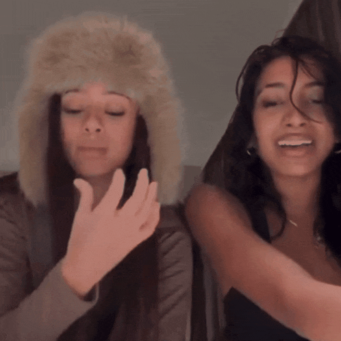 a woman wearing a furry hat stands next to another woman