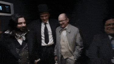 three men standing in an elevator with the number 10 on the wall behind them