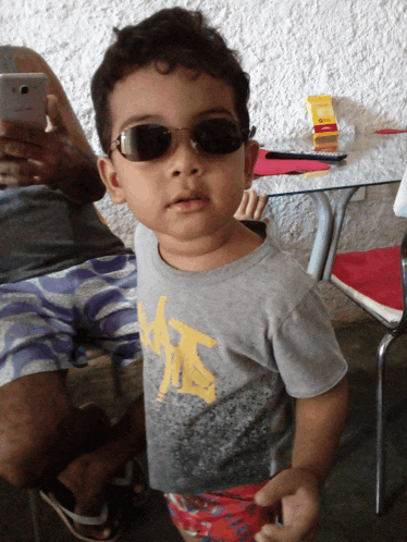 a young boy wearing sunglasses and a shirt that says ' a ' on it