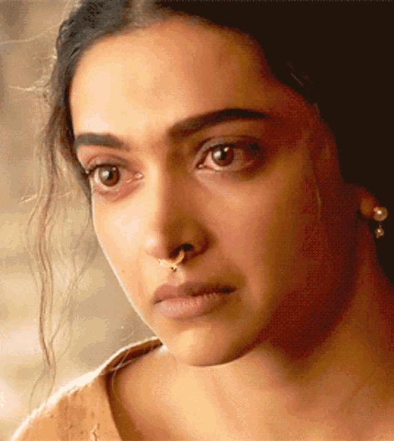 a close up of a woman with a nose ring and earrings