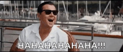 a man wearing sunglasses is sitting on a boat laughing .