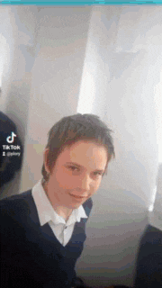 a young boy in a school uniform is sitting in a room with a laptop .