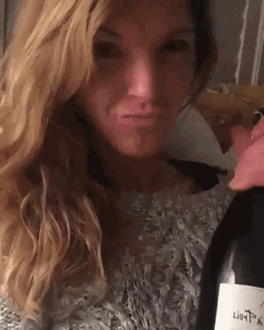 a woman is holding a bottle of wine with a label that says 2010 on it