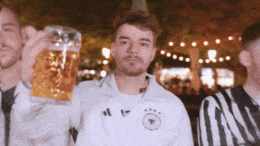 a man in a white adidas jacket is holding a beer