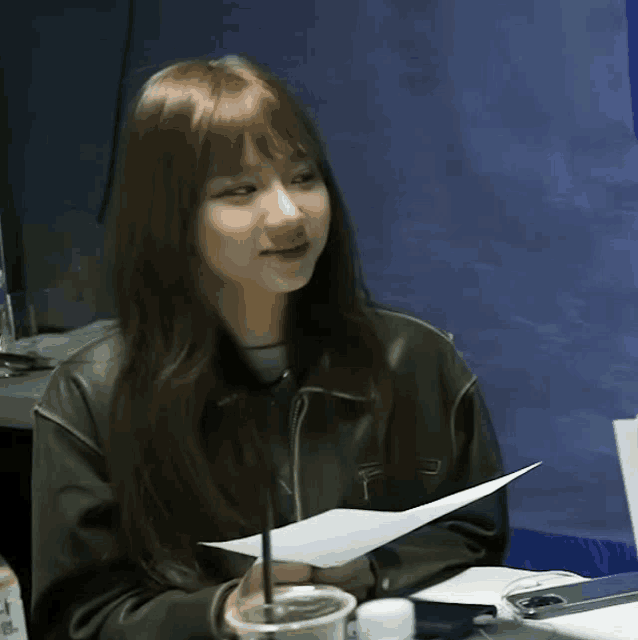 a woman in a leather jacket holds a piece of paper
