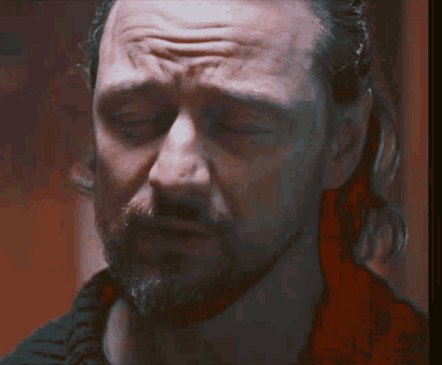 a man with a beard is crying with his eyes closed .