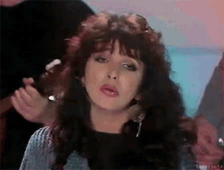 a woman with long curly hair is singing into a microphone