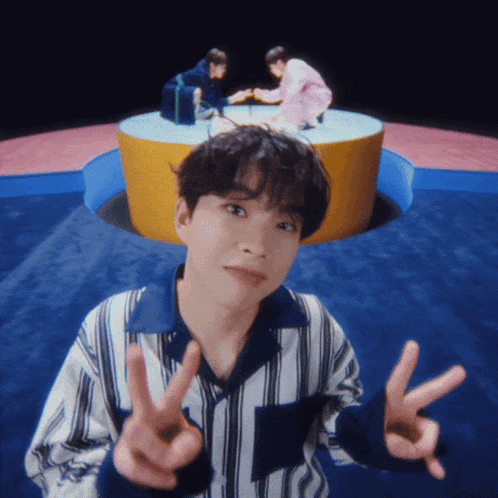 a young man giving a peace sign in front of a group of people
