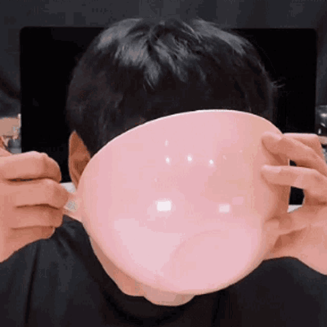 a person is holding a pink bowl in front of their face