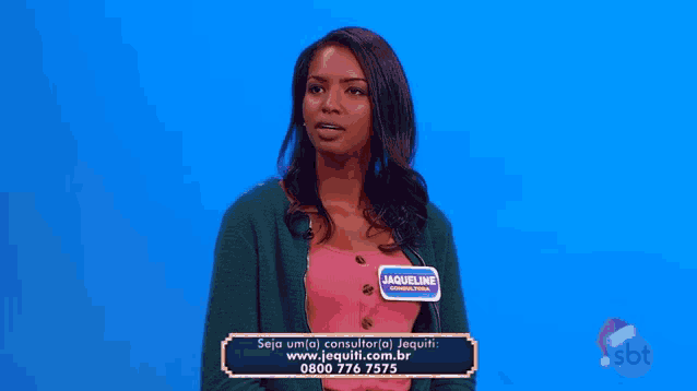 a woman in a red dress is sitting on a blue table in front of a blue curtain .