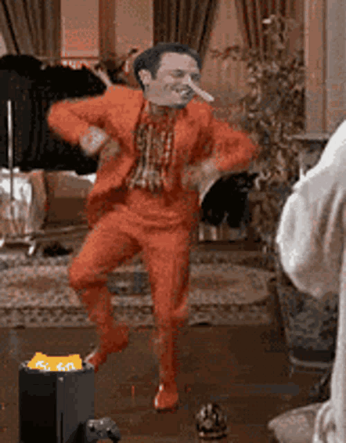 a man in a red suit is dancing in a living room