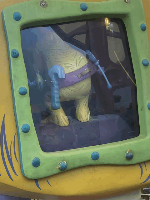 a statue of a dinosaur with a tool belt is behind a green window