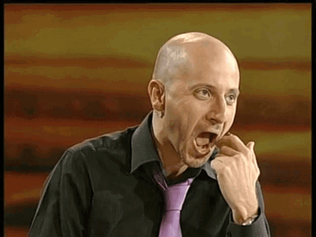 a bald man wearing a black shirt and purple tie