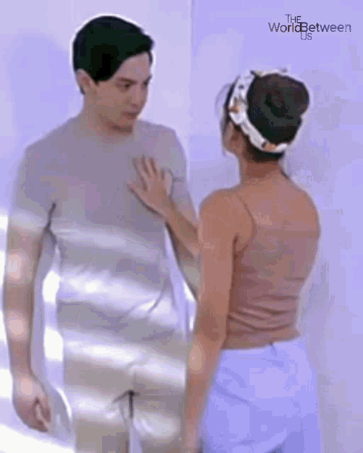 a woman is touching a man 's chest in front of a white wall .