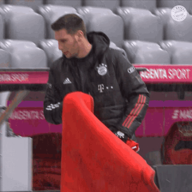 a man in a bayern munich jacket is holding a red blanket