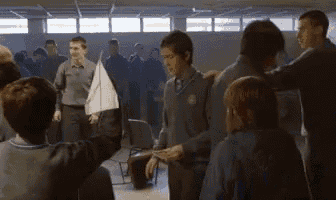 a group of people are standing in a circle with a boy holding a sailboat