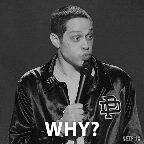 a man in a black jacket holding a microphone and asking the question why