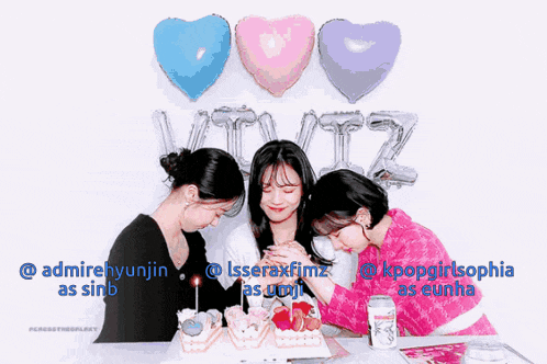 a group of girls are sitting at a table with balloons and a cake in front of them