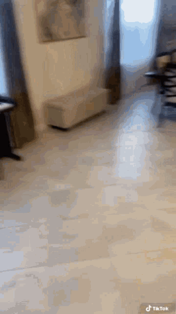 a person is standing in a living room with a white tile floor and a couch .