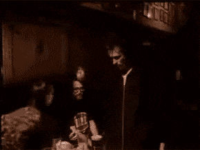 a group of people standing around a table with a man wearing a shirt that says life on it