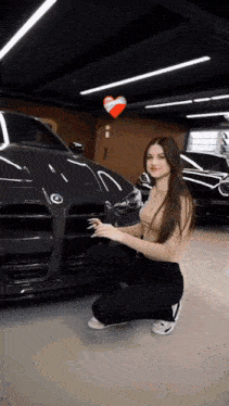 a woman is kneeling down in front of a bmw car