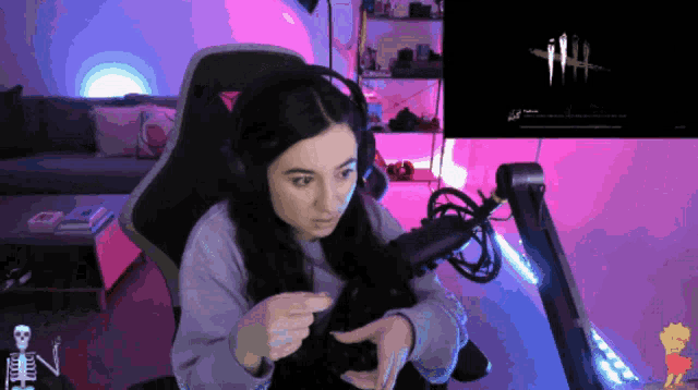 a woman wearing headphones sits in front of a microphone with a dead by daylight logo on the screen behind her