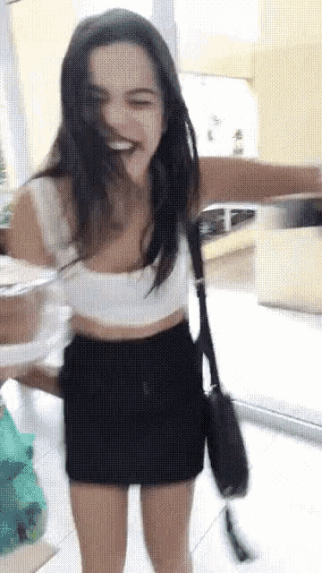 a woman wearing a black skirt and a white crop top