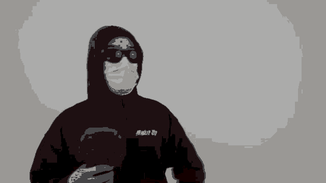 a man wearing a mask and sunglasses holds a microphone in his hand