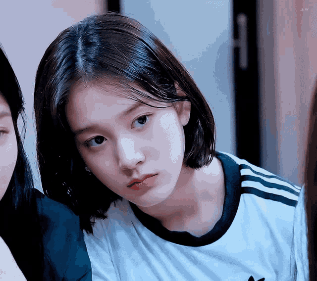 a girl with short hair is wearing a white shirt with black stripes on the side