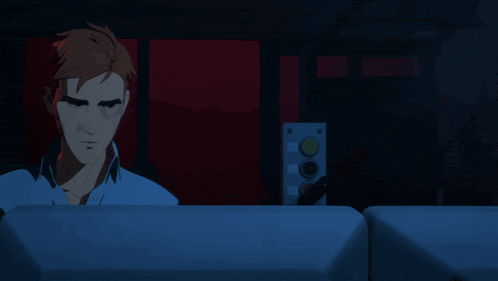 a man in a blue shirt sits in a dark room with a red background