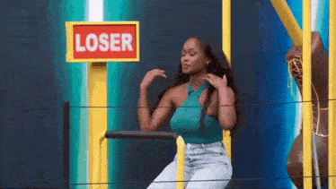 a woman is standing in front of a sign that says loser .