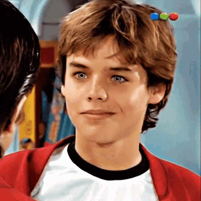 a close up of a young man 's face with a red jacket on