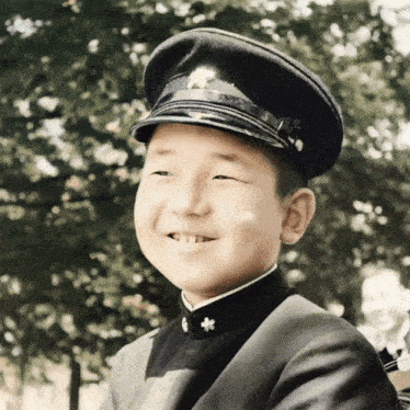a young boy wearing a black uniform and a hat smiles for the camera