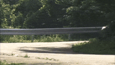 a car is driving down a road with a fence in the background