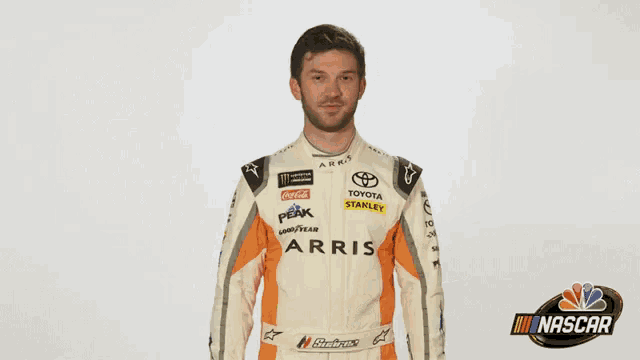 a man wearing a toyota racing suit is giving a thumbs up