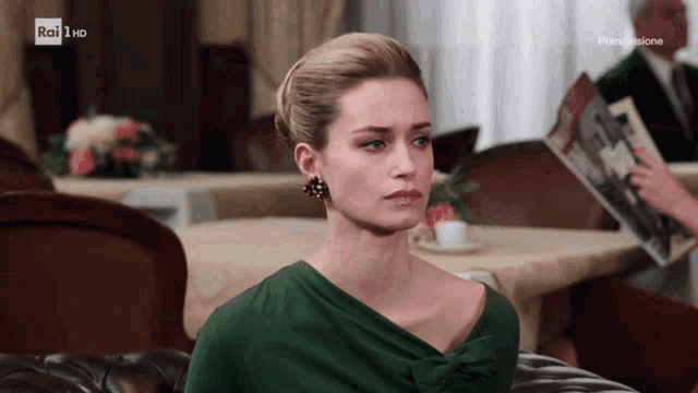 a woman in a green dress is sitting on a couch with rai 1 hd written on the bottom of the screen