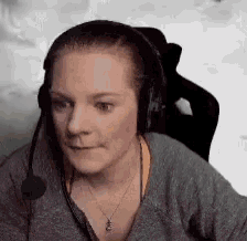 a woman wearing headphones and a microphone is sitting in a chair and making a funny face .