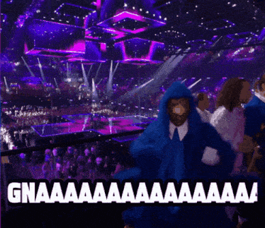 a man in a blue hoodie is standing in front of a crowd and says gnaaaa