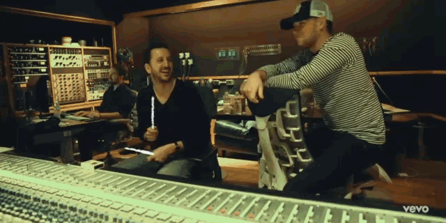 two men in a recording studio with the word vevo in the corner
