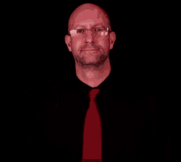 a bald man wearing glasses and a red tie is making an ok sign with his hand