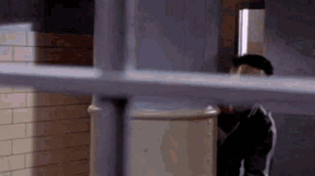 a man is peeking out from behind a fence in a room .