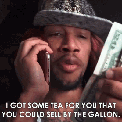 a man in a hat is talking on a cell phone while holding a dollar bill