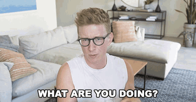 a man wearing glasses is asking what are you doing in a living room