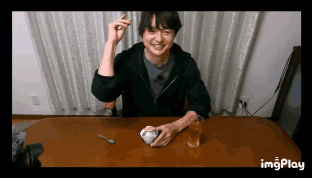 a man is sitting at a table with a bowl of food and a glass of water with imgplay written on the bottom