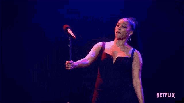 a woman is singing into a microphone on a stage .